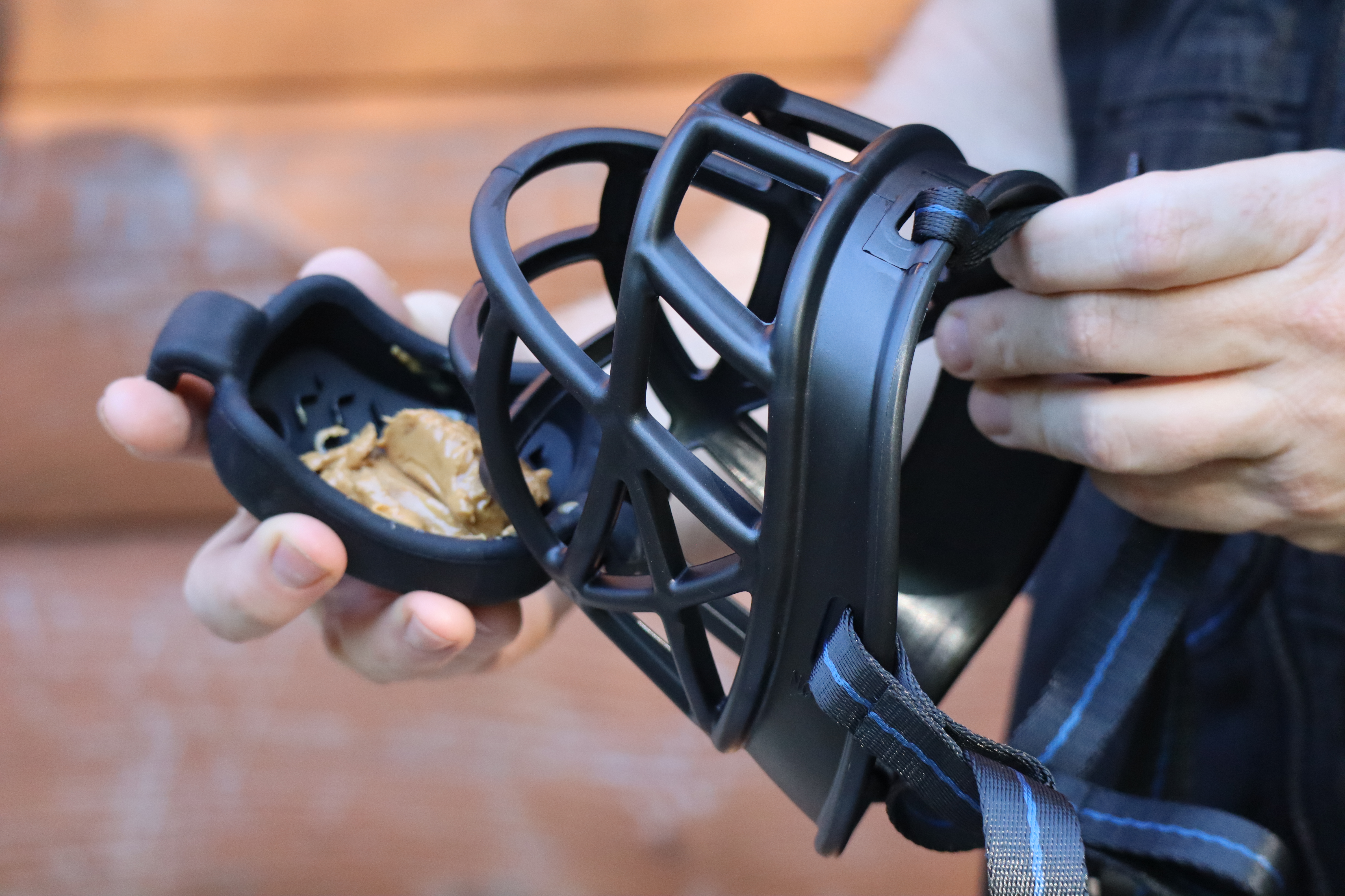 A person holding a black biothane muzzle